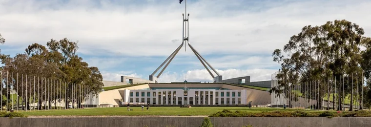 Front view of Australian Parliament House in Canberra, with an Australian flag flying above it.