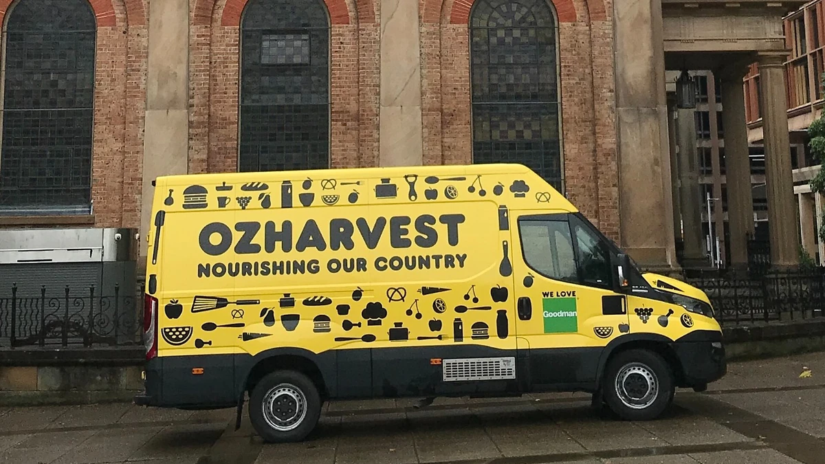 A yellow OzHarvest food delivery van parked outside St James' Church in Sydney, Australia.