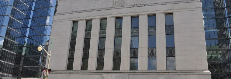 Front facade of the Bank of Canada headquarters in Ottawa, with glass office buildings on either side.