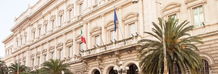 Palazzo Koch, the Bank of Italy headquarters in Rome, with its stone facade, entrance and national flags.