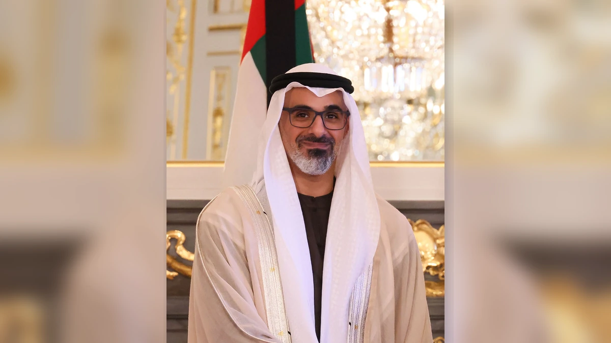 Portrait of Sheikh Khaled bin Mohamed bin Zayed Al Nahyan with a UAE flag behind him.