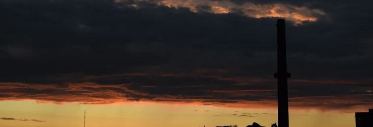 Horne Smelter and its tall smokestack silhouetted against an orange twilight sky in Rouyn-Noranda, Quebec.