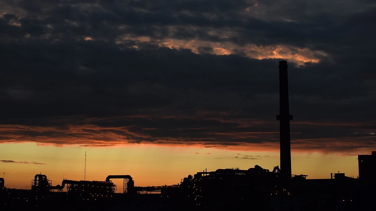 Horne Smelter and its tall smokestack silhouetted against an orange twilight sky in Rouyn-Noranda, Quebec.