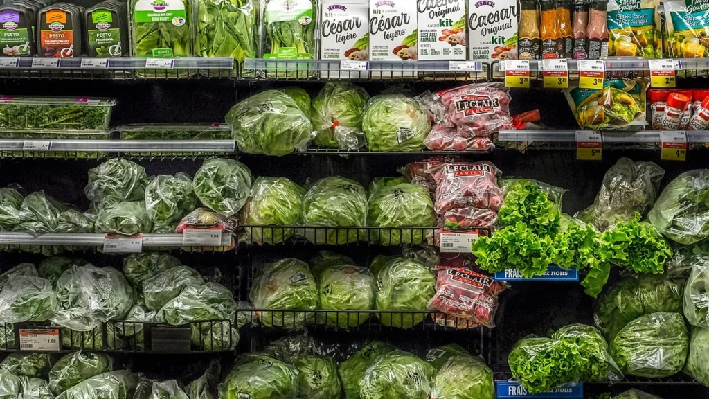 Packaged salads, leafy greens and fresh produce displayed on shelves at an IGA supermarket in Quebec City.