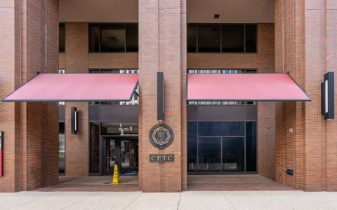 Entrance to the Commodity Futures Trading Commission offices in Washington, D.C., with the CFTC seal on a brick column.