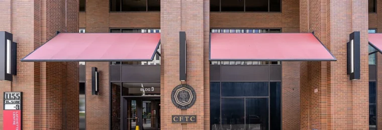 Entrance to the Commodity Futures Trading Commission offices in Washington, D.C., with the CFTC seal on a brick column.