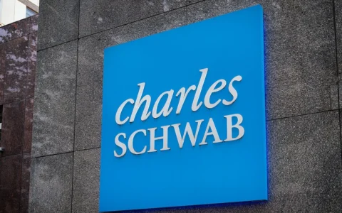 Large blue Charles Schwab sign mounted on the facade of an office building in Bethesda, Maryland.
