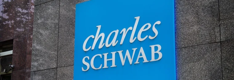 Large blue Charles Schwab sign mounted on the facade of an office building in Bethesda, Maryland.