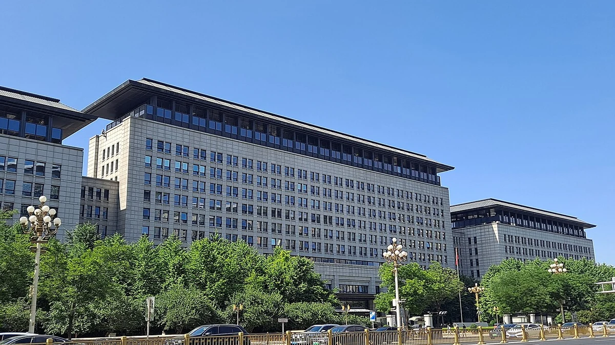 Exterior of China’s Ministry of Commerce building, with trees and vehicles along the street.