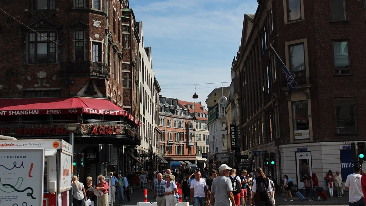 Pedestrians walking past shops and restaurants along Strøget in Copenhagen, Denmark.