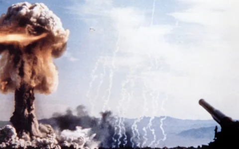 Mushroom cloud above the Nevada desert during the 1953 Grable nuclear test, with an artillery cannon on the right.