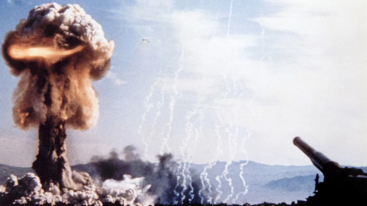 Mushroom cloud above the Nevada desert during the 1953 Grable nuclear test, with an artillery cannon on the right.