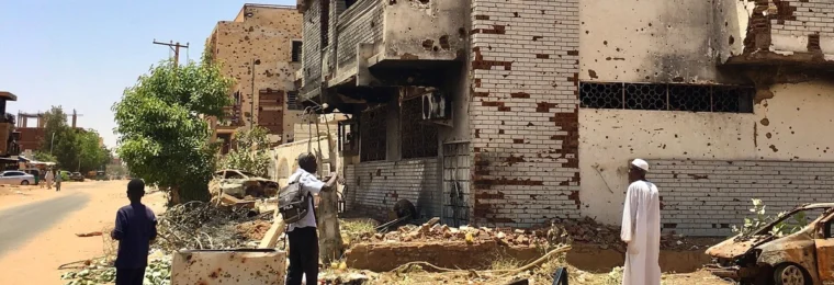 Damaged multi-storey building with scarred walls and exposed brickwork in the Wad Nubawi neighborhood of Omdurman, Sudan.