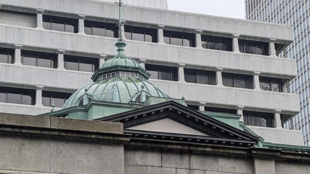 Bank of Japan building in Tokyo with its green copper dome in front of a modern office building.