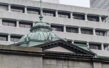 Bank of Japan building in Tokyo with its green copper dome in front of a modern office building.