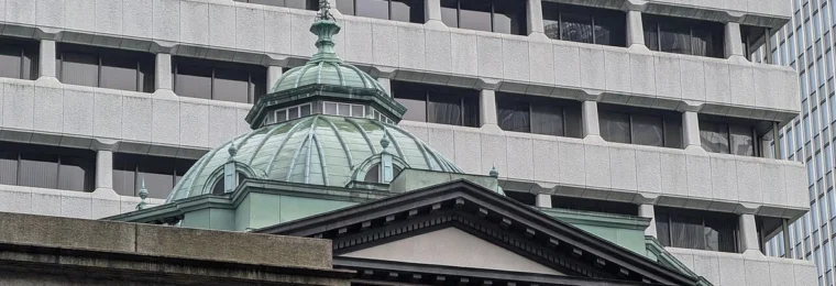 Bank of Japan building in Tokyo with its green copper dome in front of a modern office building.