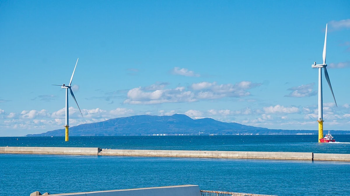 Two offshore wind turbines at Akita Port in Japan, with the Oga Peninsula across the water.