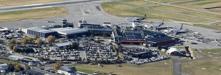 Aerial view of Queenstown Airport with its runway, terminal buildings and parked aircraft in New Zealand.
