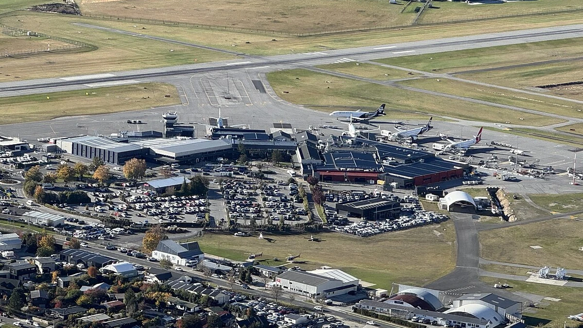 Aerial view of Queenstown Airport with its runway, terminal buildings and parked aircraft in New Zealand.