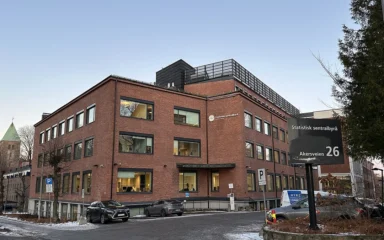 Statistics Norway office building at Akersveien 26 in Oslo, with agency signage and a parking area.
