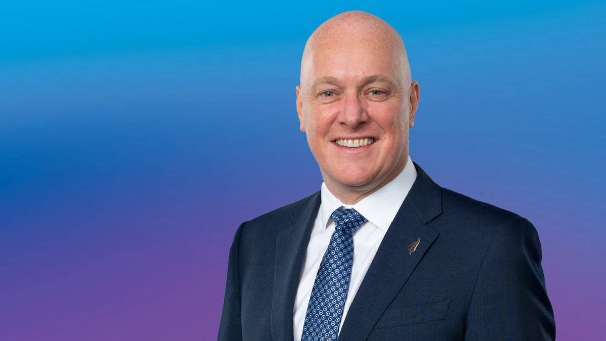 Portrait of Christopher Luxon, New Zealand National Party leader, in a navy suit against a blue and purple background.