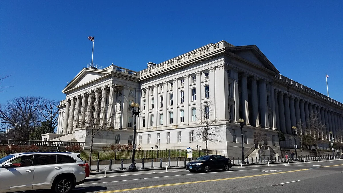 Exterior of the U.S. Treasury Building in Washington, D.C., seen from the street under a clear blue sky.
