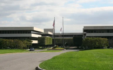 Exterior of PepsiCo’s headquarters complex in Purchase, New York, with flagpoles, a driveway and lawn.