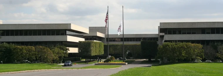 Exterior of PepsiCo’s headquarters complex in Purchase, New York, with flagpoles, a driveway and lawn.
