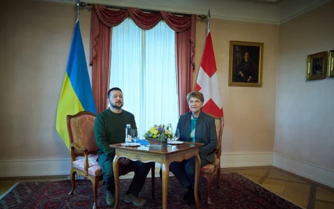 National flags of Ukraine and Switzerland stand behind officials at a meeting in Switzerland.
