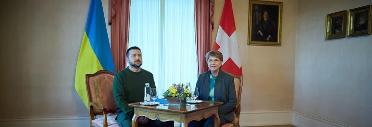 National flags of Ukraine and Switzerland stand behind officials at a meeting in Switzerland.
