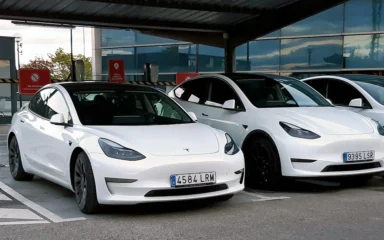 White Tesla Model 3 and Model Y vehicles parked side by side.