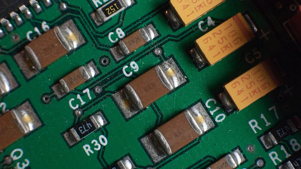 Close-up of multilayer ceramic capacitors and other components mounted on a green printed circuit board.