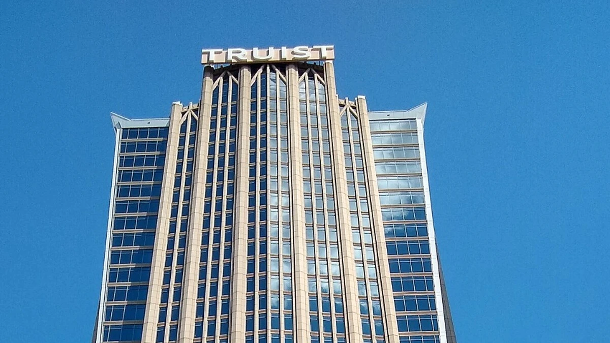 Top of Truist Center in Charlotte, North Carolina, with TRUIST lettering above its tower against a blue sky.