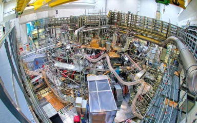 Wide-angle overhead view of the Wendelstein 7-X stellarator inside its torus hall in Greifswald, Germany.