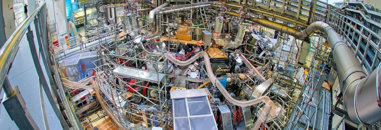 Wide-angle overhead view of the Wendelstein 7-X stellarator inside its torus hall in Greifswald, Germany.