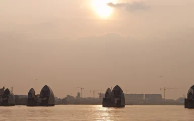 Thames Barrier flood gates on the River Thames in London beneath a sunlit sky.