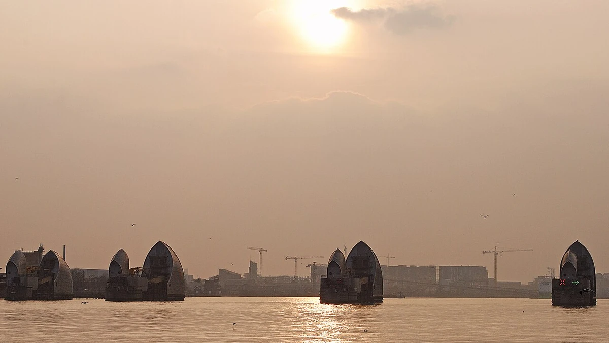 Thames Barrier flood gates on the River Thames in London beneath a sunlit sky.