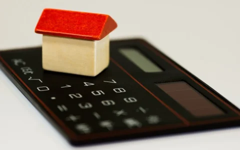 Household budgeting concept with a small home model on a calculator.
