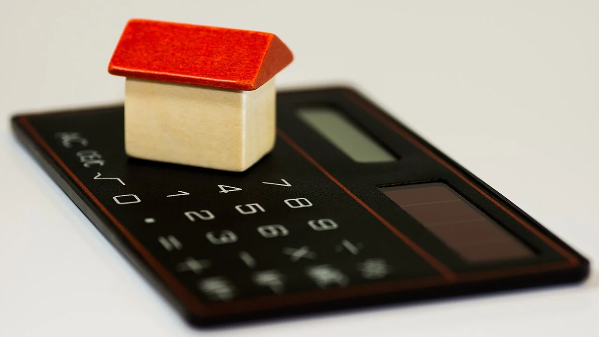 Household budgeting concept with a small home model on a calculator.