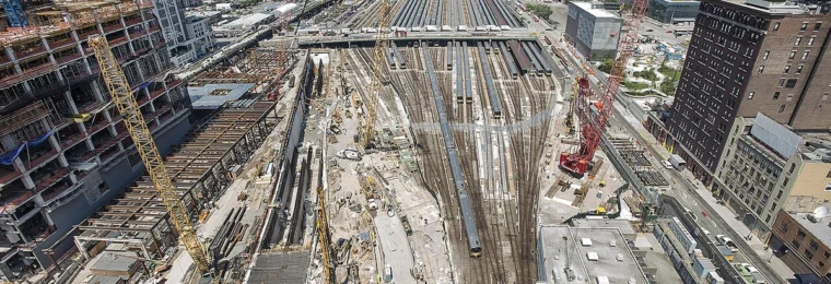 Construction activity at Hudson Yards in Manhattan with cranes, rail yard tracks and surrounding buildings.