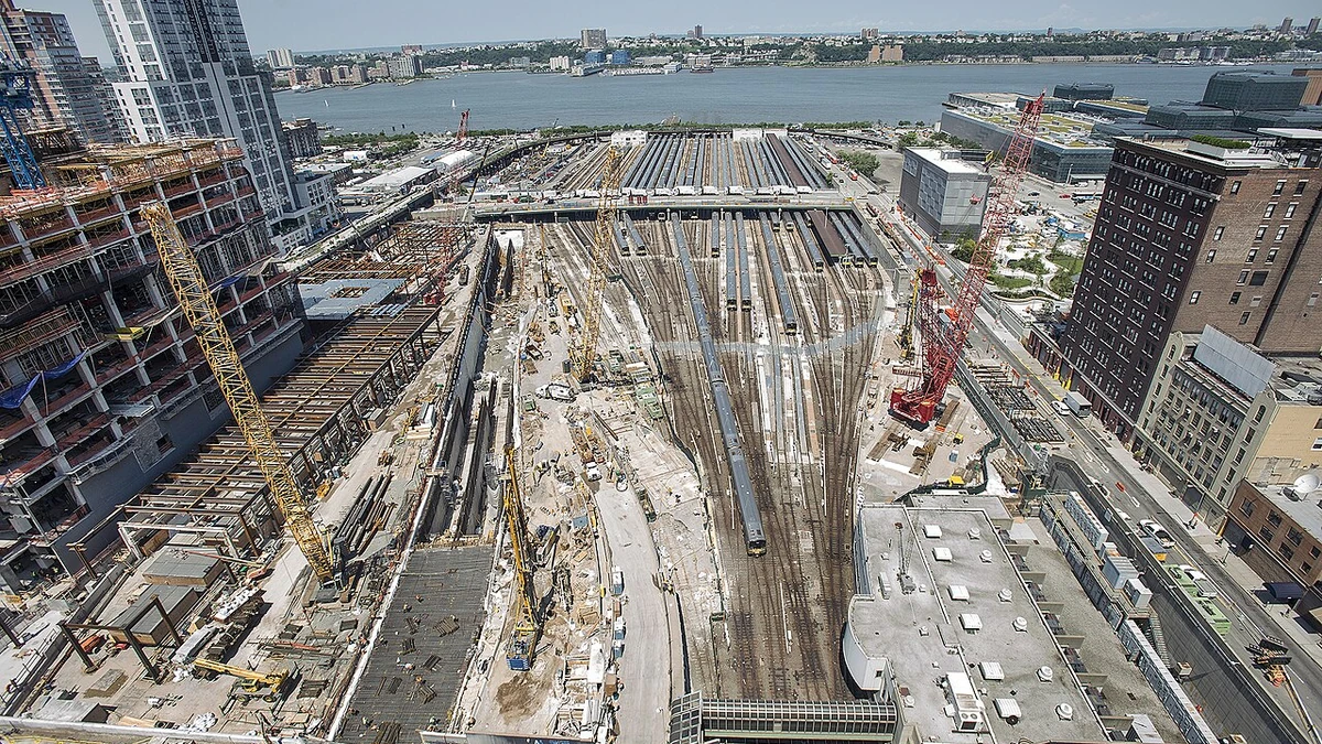 Construction activity at Hudson Yards in Manhattan with cranes, rail yard tracks and surrounding buildings.