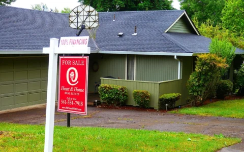 A red Heart & Home Real Estate for-sale sign outside a house in Eugene, Oregon.