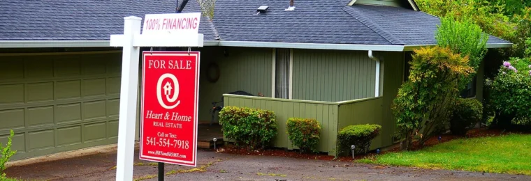 A red Heart & Home Real Estate for-sale sign outside a house in Eugene, Oregon.