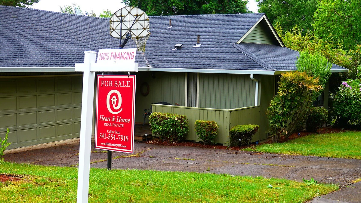 A red Heart & Home Real Estate for-sale sign outside a house in Eugene, Oregon.