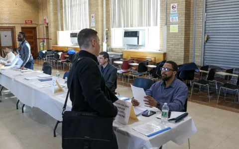 Job applicant speaking with a recruiter across a table at a New York City Transit job fair in Brooklyn.