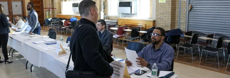 Job applicant speaking with a recruiter across a table at a New York City Transit job fair in Brooklyn.