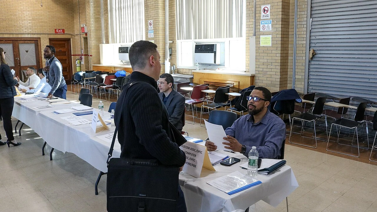 Job applicant speaking with a recruiter across a table at a New York City Transit job fair in Brooklyn.