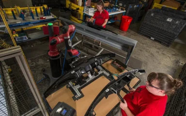 Workers and a collaborative robot on a factory floor at Tennplasco in Lafayette, Tennessee.
