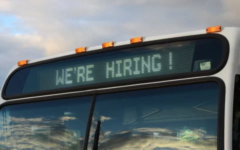 A TriMet bus in Portland, Oregon, displaying a We're Hiring sign on its electronic destination display.