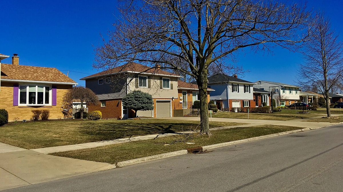 Detached suburban houses along Forest Hill Drive in Amherst, New York, beneath a blue sky.
